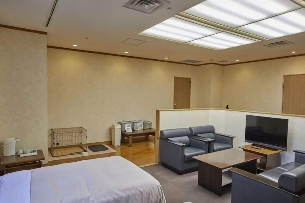 A hotel room with a bed, a TV, a sofa, a coffee table, and a desk.