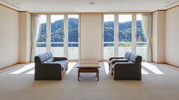 A room with two sofas facing a large window, a small table in the center, and a view of a mountainous landscape.