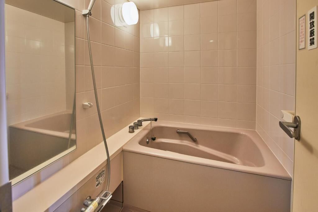 A bathroom with a bathtub, a shower, and a mirror.