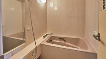 A bathroom with a bathtub, a shower, and a mirror.