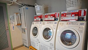 A laundry area with multiple washing machines and dryers, a water heater, and a basket on the wall. - Nagano Daiichi Hotel (Nagano)