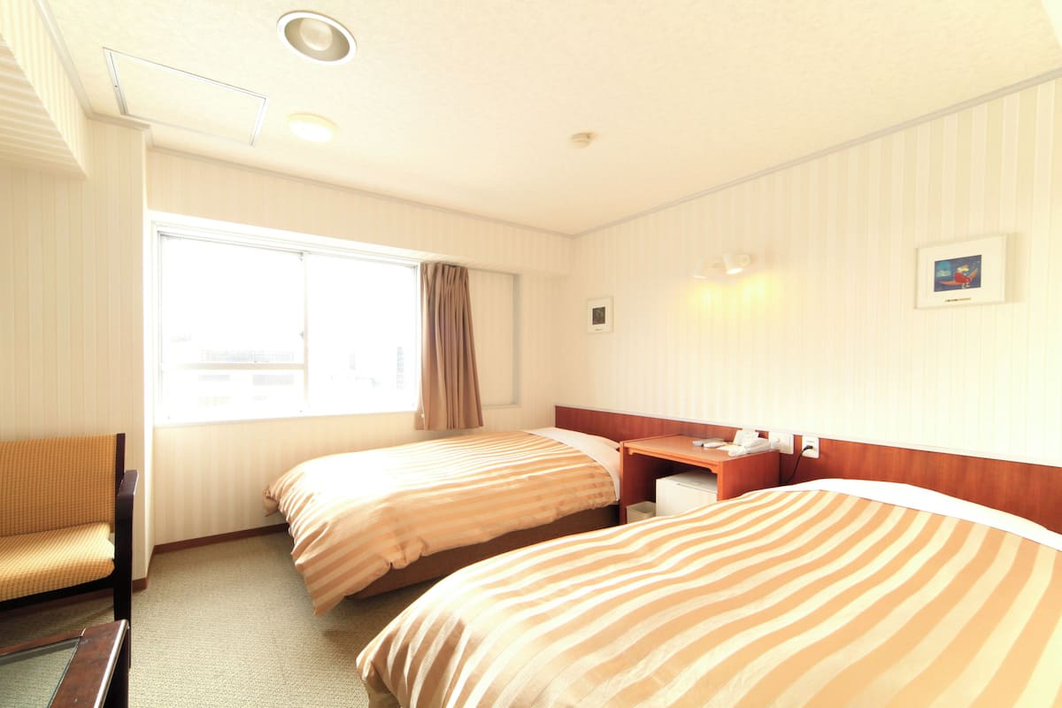 Una habitación de hotel con dos camas, un escritorio, una silla y un televisor.