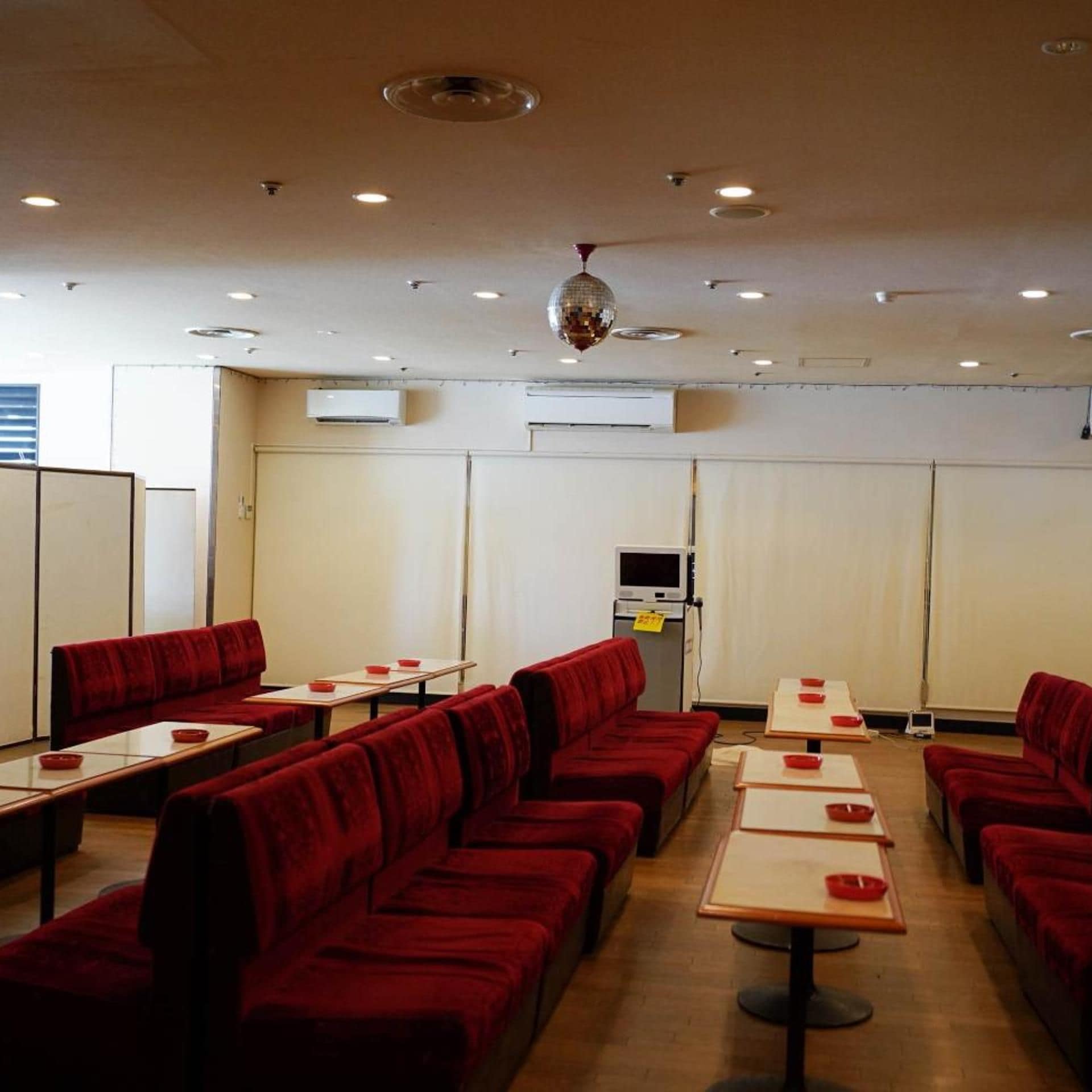A restaurant with booth seating and tables, air conditioning units, and a disco ball.
