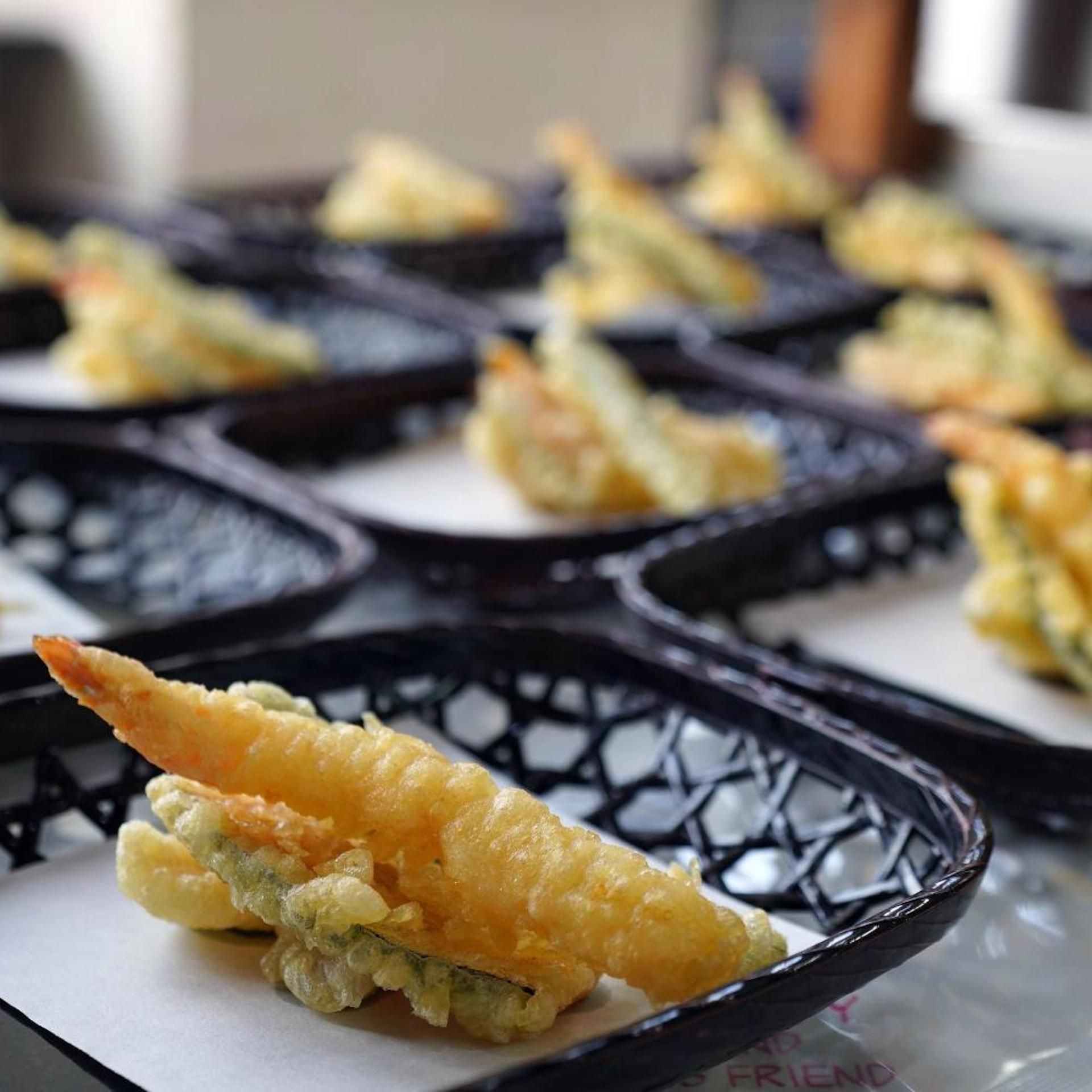 A tray of food items, likely tempura, served in black bowls.