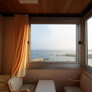 A room with a large window, two chairs, a small table, and a curtain. - Grand Hotel Taiyo (Minamiboso)