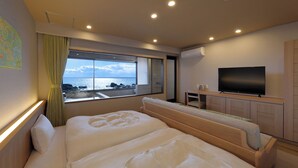 Een hotelkamer met twee bedden, een televisie en uitzicht op zee.