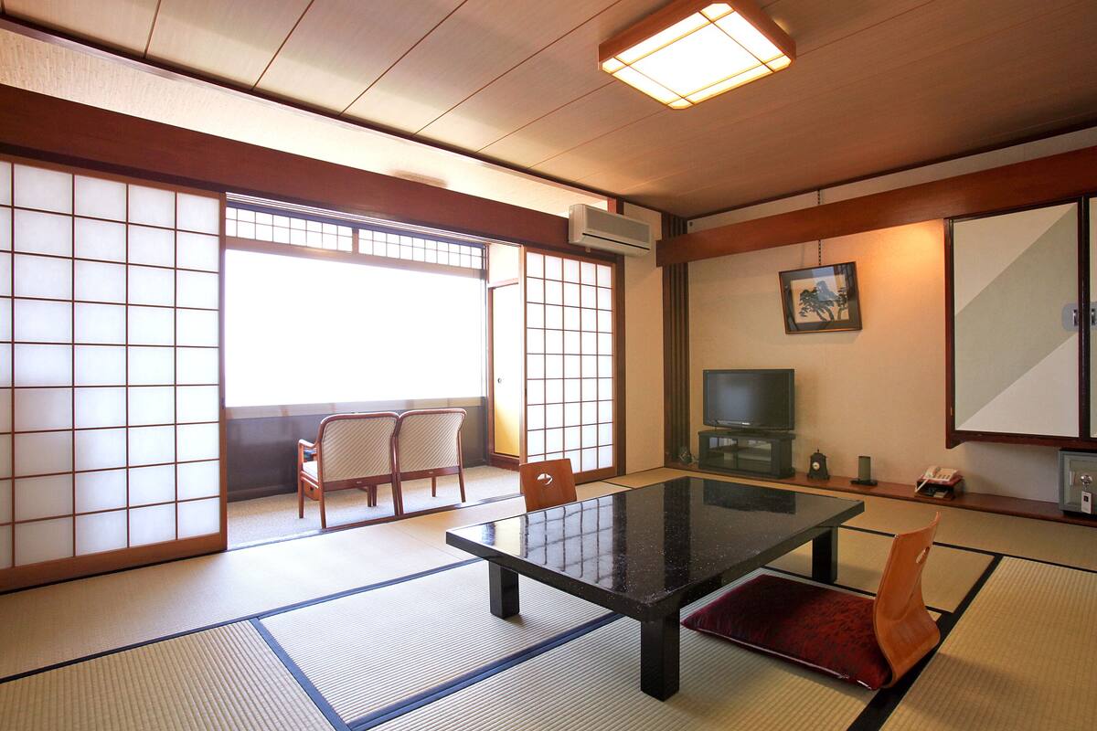Une pièce de style japonais traditionnel, avec un sol recouvert de tatamis, une table basse et des portes coulissantes.