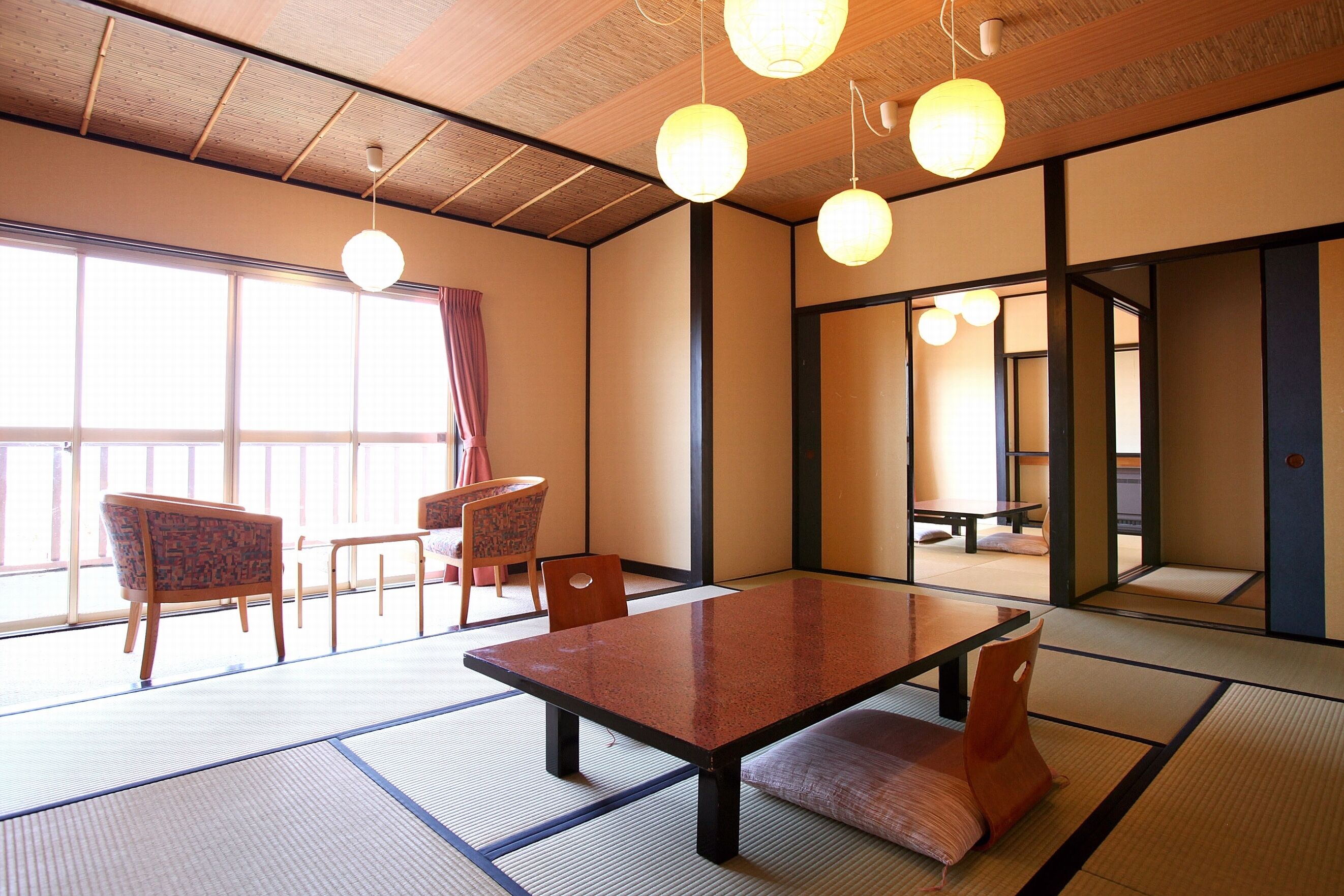 Perinteinen japanilainen huone, jossa on tatamimatto, matala pöytä ja tuolit.