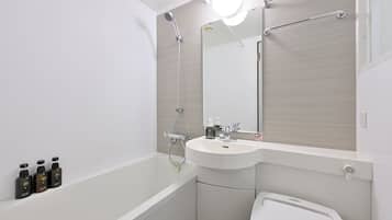 A modern bathroom with a white sink, a mirror, and a shower. There are three bottles of shampoo on the wall.