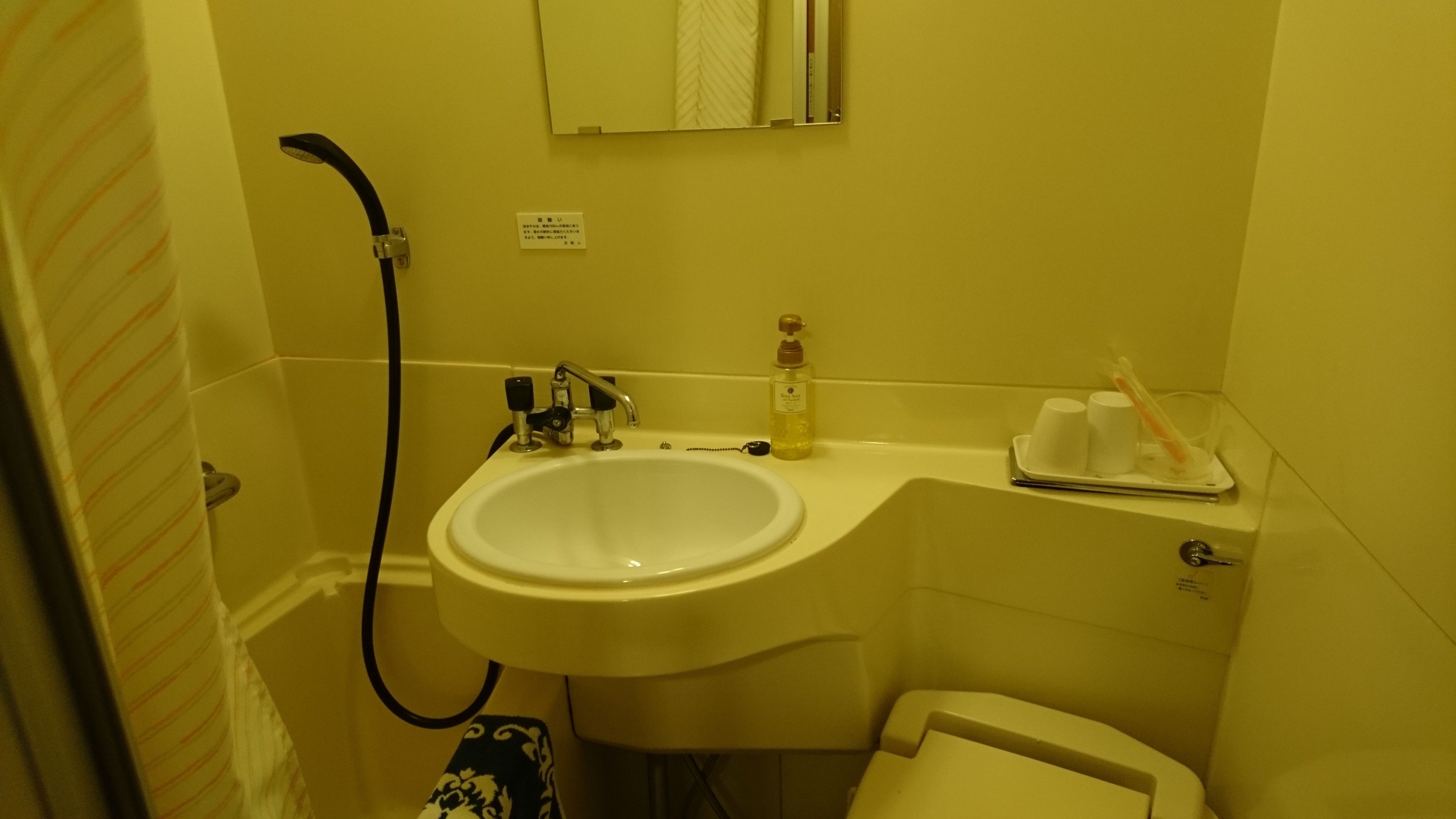 Um banheiro com pia, espelho, porta-toalhas e vaso sanitário.
