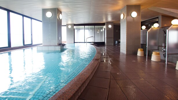 Una piscina interior con agua cristalina, rodeada de paredes y suelo de baldosas.