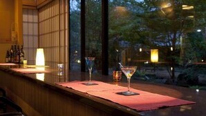 Zona de bar con mostrador de madera, dos copas de martini y una botella de licor.