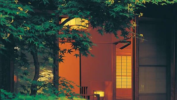Una habitación japonesa tradicional con suelo de tatami, una mesa baja y una puerta corredera.