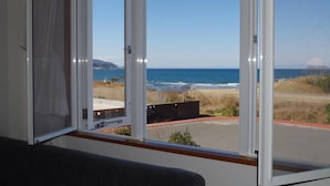 A room with a large window overlooking a beach and ocean. - Hotel Familio Tateyama (Tateyama)