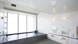 A modern bathroom with a large bathtub, a shower area, and a window providing natural light. - Hotel Familio Tateyama (Tateyama)