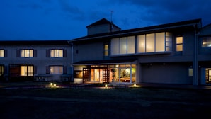 A modern two-story house with a large glass entrance and a well-lit interior. - Hotel Familio Tateyama (Tateyama)