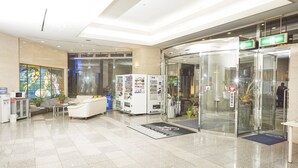Eine Lobby mit Empfangstresen, Sitzgelegenheiten, Verkaufsautomaten und einem Glastunnel.