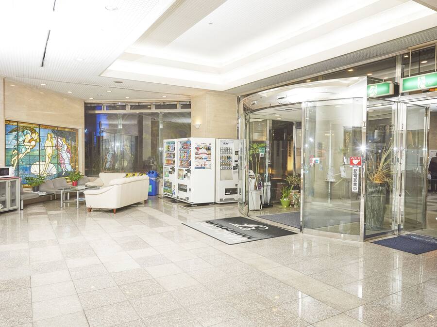 A lobby with a reception desk, seating area, vending machines, and a glass elevator.