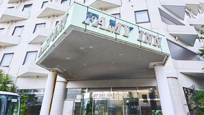 Ein modernes Gebäude mit markantem, winkelförmigem Design, inklusive einer auffälligen Eingangspartei mit Vordach und dem Schild 'AMY INN'.