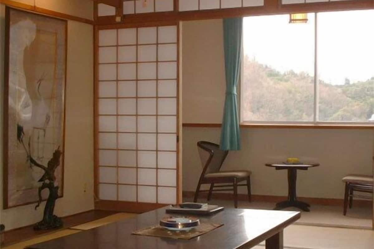 Une pièce de style japonais traditionnel, avec un sol recouvert de tatamis, une table basse, une chaise et un tableau accroché au mur.