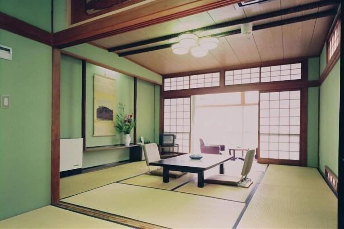 Une pièce de style japonais traditionnel, avec un sol recouvert de tatamis, une table basse et des portes coulissantes.