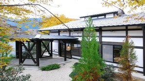 En traditionell japansk byggnad med en täckt uteplats, en träkonstruktion och en liten trädgård med växter.
