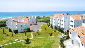 A coastal hotel with white buildings and red-tiled roofs, a paved driveway, and a view of the ocean. - Tateyama Resort Hotel (Tateyama)