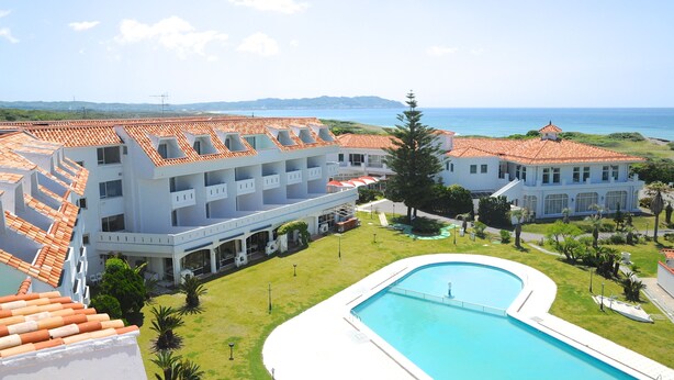A resort with a swimming pool, multiple buildings with red-tiled roofs, and a view of the sea. - Tateyama Resort Hotel (Tateyama)