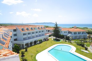 A resort with a swimming pool, multiple buildings with red-tiled roofs, and a view of the sea. - Tateyama Resort Hotel (Tateyama)