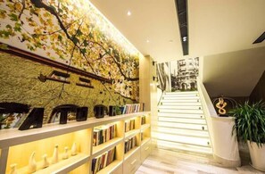 A modern interior with a staircase, bookshelves, and a wall with a leaf pattern. - Atour Hotel Hongqiao National Exhibition Center Shanghai (Shanghai)