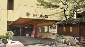 Um edifício com entrada tradicional japonesa, um banco de madeira e um espelho d'água em pedra.