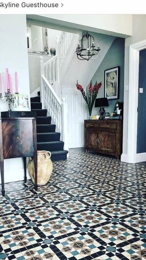 Stunning interior with a geometric patterned floor, staircase, and elegant chandelier.