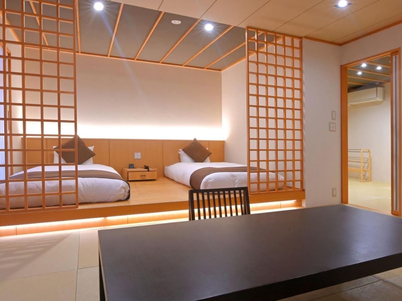 A room with two beds, a table, and a chair.