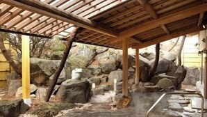 A hot spring area with a stone pool, wooden pergola, and surrounding rocks. - Nunohan (Suwa)