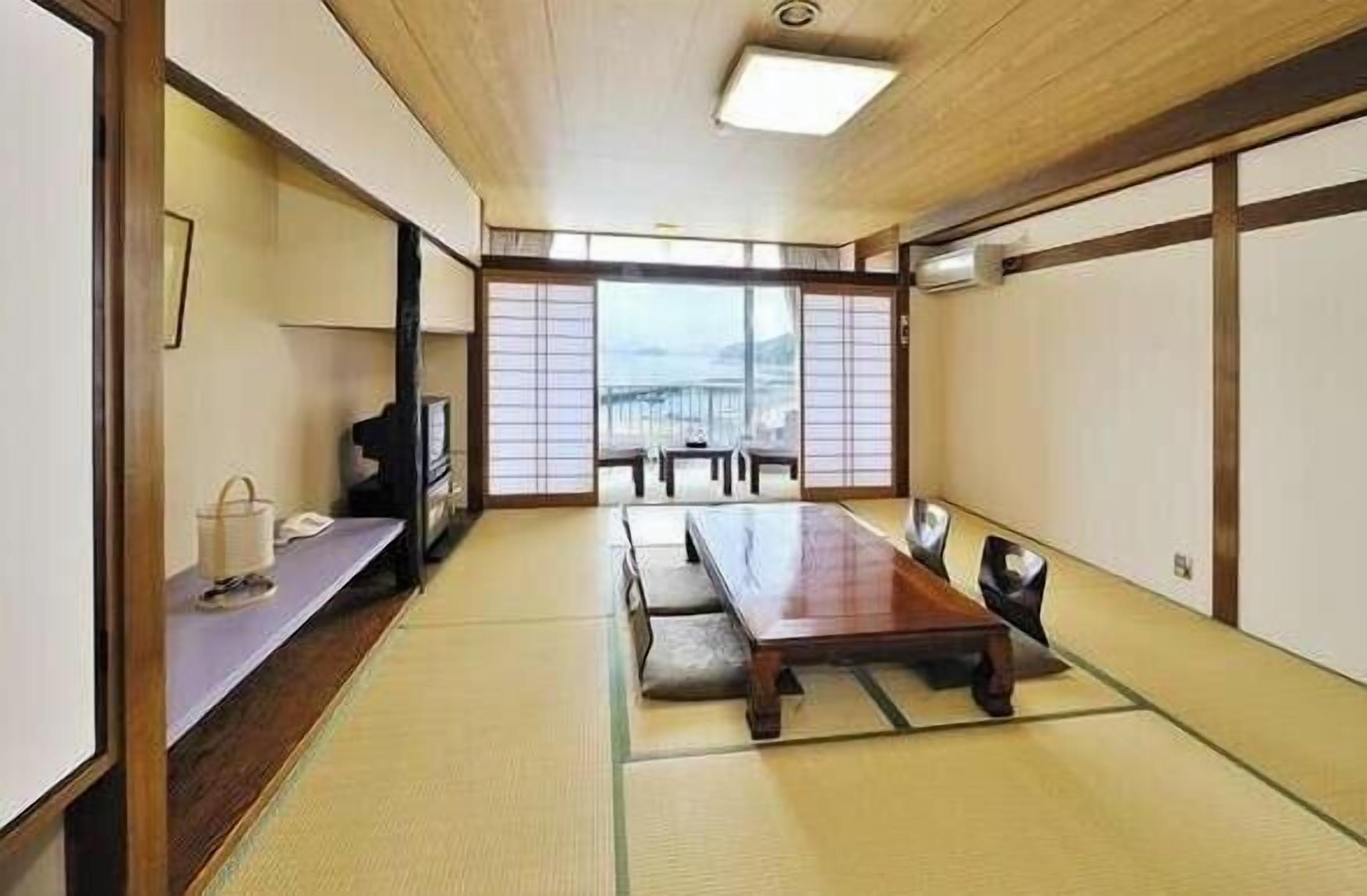 Une pièce de style japonais traditionnel, avec un sol recouvert de tatamis, une table basse et des portes coulissantes.