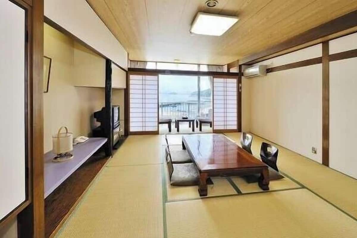 Una habitación japonesa tradicional con suelo de tatami, una mesa baja y puertas correderas.