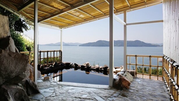 A stone-walled room with a view of a lake and mountains. - Washu Onsen Bizenya Koushi (Kurashiki)