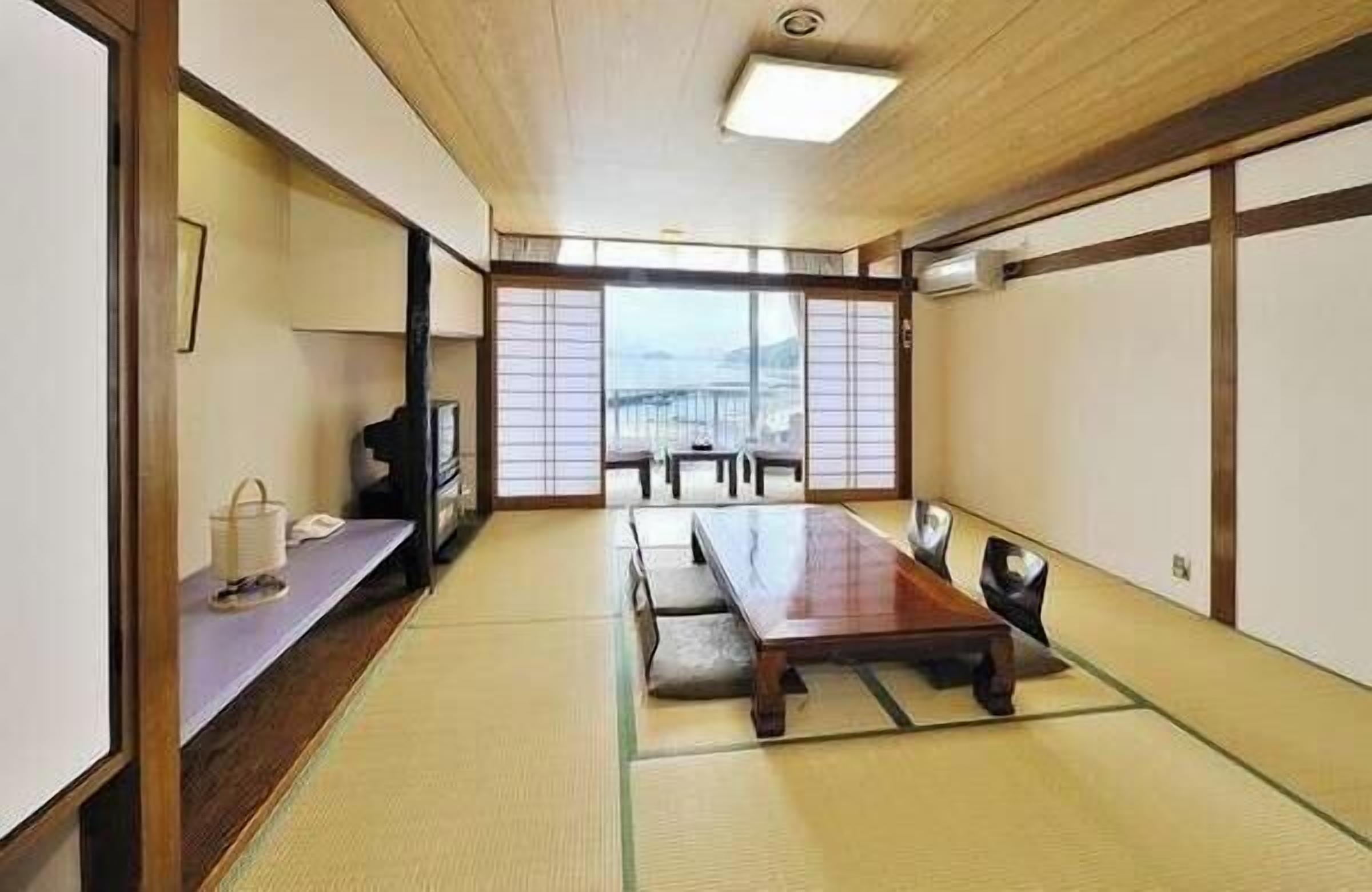 A traditional Japanese room with tatami flooring, a low table, and sliding doors.