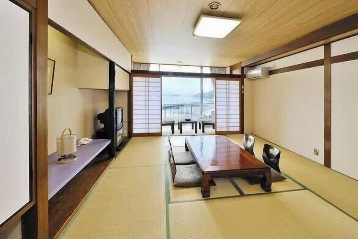 Una habitación japonesa tradicional con suelo de tatami, una mesa baja y puertas correderas.