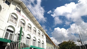A white building with arched windows and balconies, a green staircase, and a clear sky with clouds. - Shiga Swiss Inn (Yamanouchi)