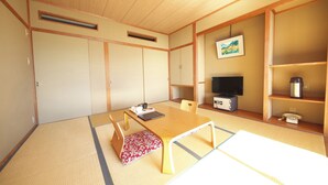 Una habitación japonesa tradicional con suelo de tatami, una mesa baja, un televisor y un teléfono antiguo.