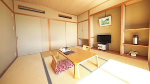 A traditional Japanese room with tatami flooring, a low table, a television, and a vintage telephone.
