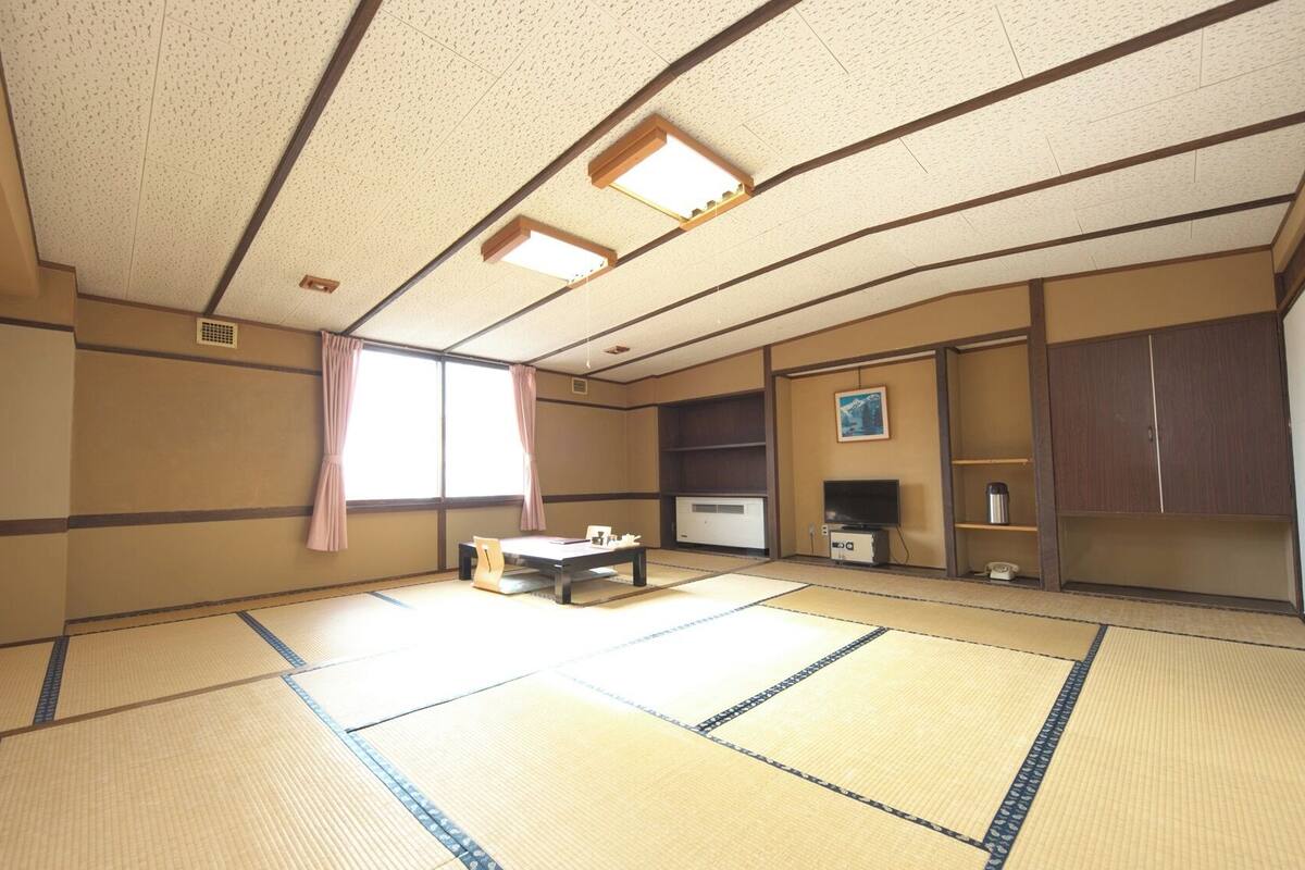 A traditional tatami mat room with a television, a small table, and a cabinet.