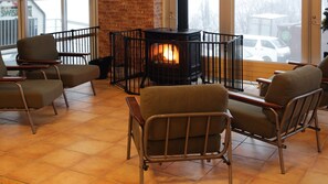 A cozy room with a fireplace, comfortable seating, and a view through large windows.