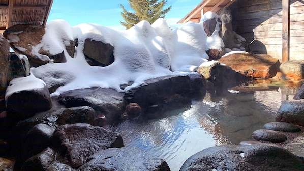 A hot spring area with rocks and water, surrounded by wooden structures.