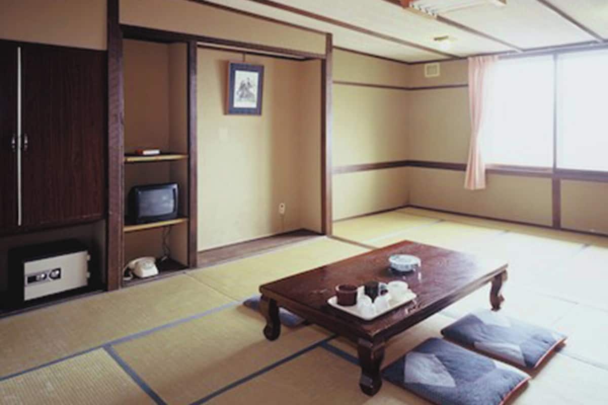 Ein Raum mit Tatami-Matten, Tatami-Mattenboden, einem Holztisch mit Tablett und einem Kleiderschrank.