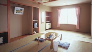 Una habitación japonesa tradicional con suelo de tatami, una mesa baja, un futón y un puertas correderas.