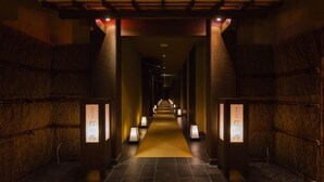 A hallway with a carpeted floor, illuminated by wall-mounted lamps, and flanked by textured walls. - Yukyo No Hibiki Yusai (Minamioguni)