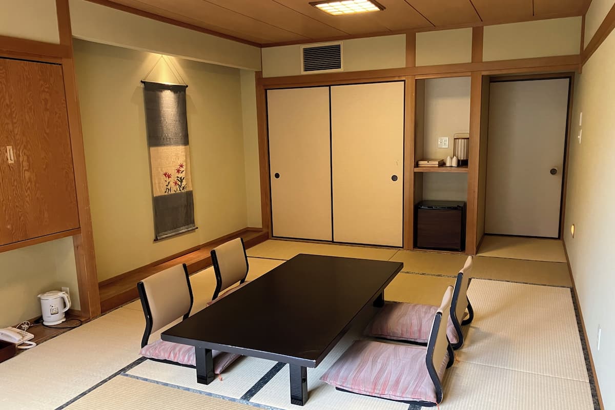 Une pièce de style japonais traditionnel, avec un sol recouvert de tatamis, une table basse et des portes coulissantes.