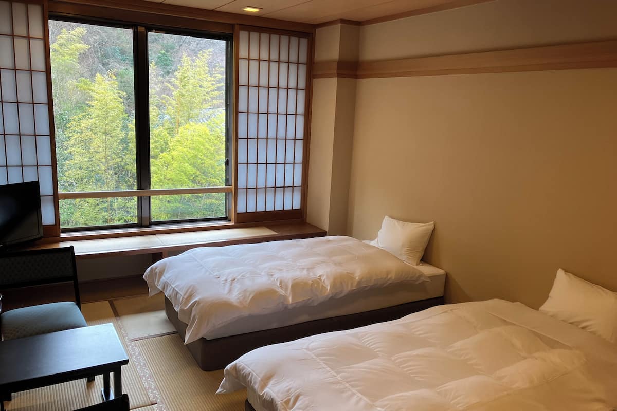 Une chambre d’hôtel avec deux lits, un bureau et une télévision.